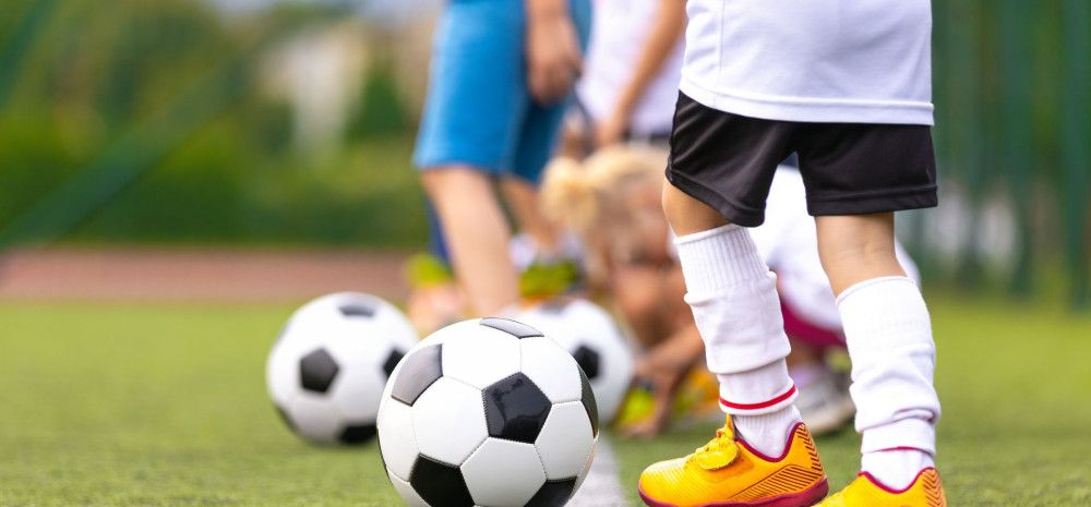 A number of children playing soccer, the picture only shows their legs and soccer balls.