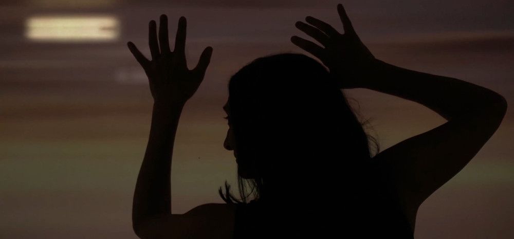 Silhouette of a lady with her arms up in the air 
