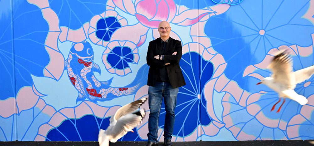 Cr Sean O'Reilly standing in front of a mural