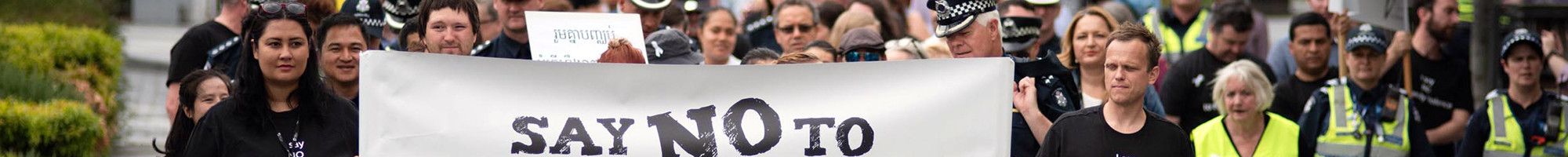 A large group marching with a sign saying 'We say no to family violence' 