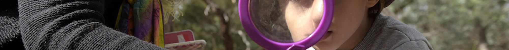 Child discovering nature through a magnifying glass.