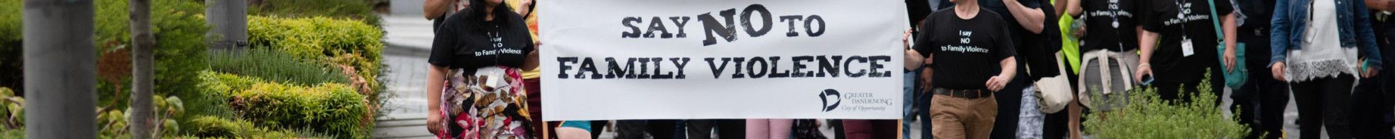 A crowd walks behind the Walk Against Family Violence banner