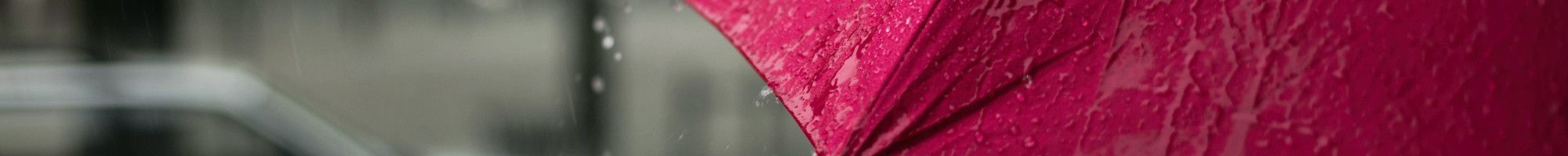 A red umbrella getting rained on.