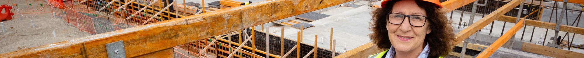 A woman dressed in a high vis vest and a hard hat stands on a platform overlooking a worksite