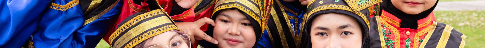 A group of smiling children wearing traditional Indonesian clothing