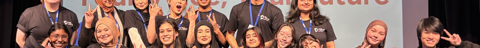 A large group of young people pose together on a stage in front of a sign that reads Youth Summit 2025