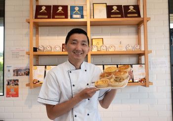 Man holding a tray of pies at his business