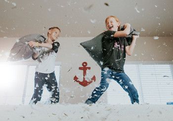 Kids jumping on a bed pillow fighting