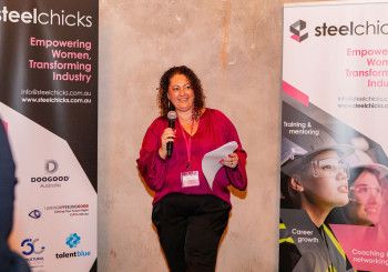 A lady talking holding a microphone and paper