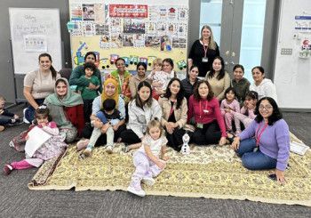 A large group of mums and their children smiling at the camera