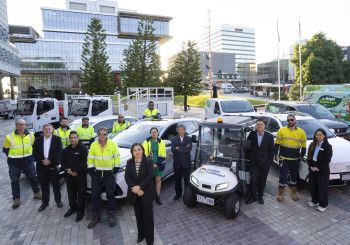 A small crowd of people standing next to a range of electric vehicles