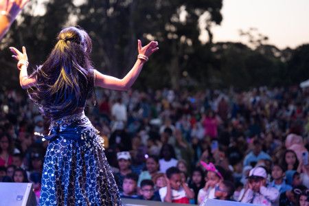 A woman dances on stage in front of a large crowd