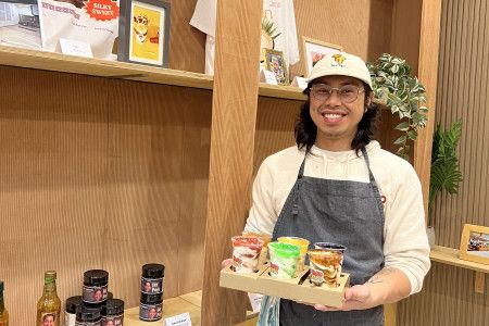 A smiling man holds a tray of sweet treats