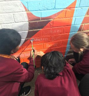 Children signing their name to the brick wall artwork