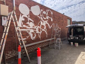 Brick wall with the outlines of the artwork beginning to take shape