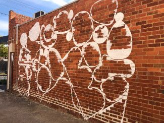 Brick wall with completed white outlines of artwork 