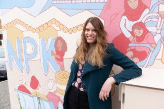 Sasha Heath standing in front of 'The Noble Community' mural