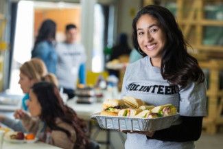 a charity volunteer holding a tray of food