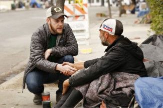 a person assisting a person sitting in the street