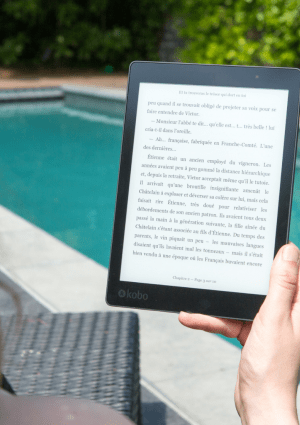 A woman reading an ebook by a pool on a device