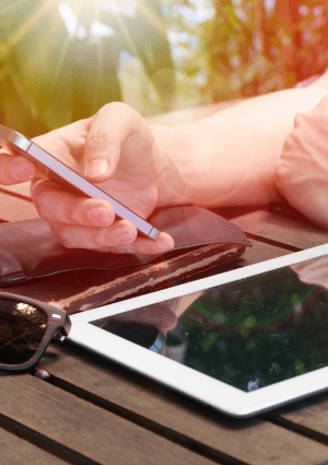 Person reading a book on a phone with another device on a table