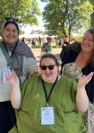 Three people smiling and waving at the camera.